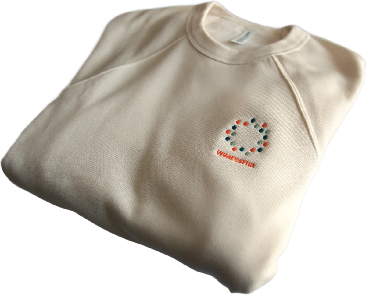 A folded cream SRNA sweatshirt with a circle of dots and &ldquo;wearesrna&rdquo; embroidered on the chest.